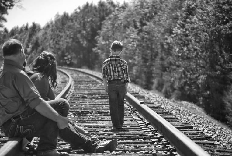 boy parents walking railroad