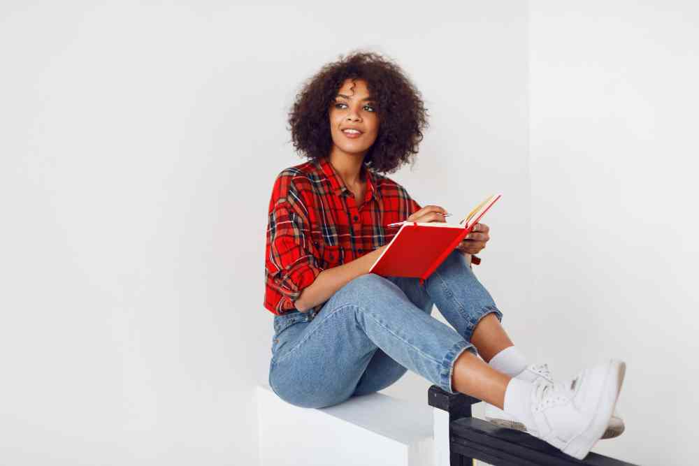 pensive african student girl resting with notebook wearing red checkered shirt blue jeans 11zon