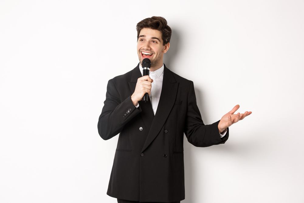 portrait handsome man black suit singing song holding microphone giving speech standing against white background 11zon