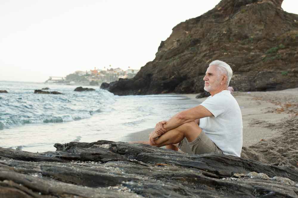 senior man resting beach admiring ocean 11zon