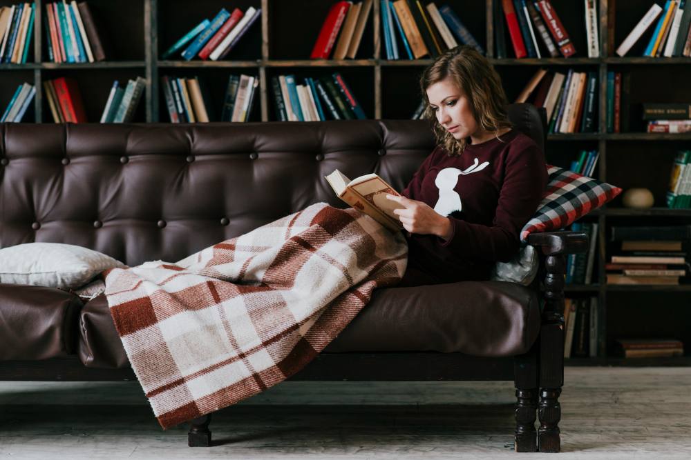 woman with blanket reading book 11zon